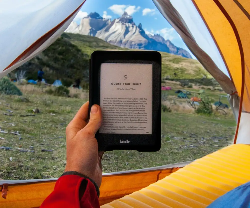 Kindle being read in an open tent with a mountain in the background